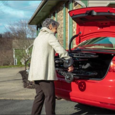 Lady putting the Feather Lightweight Wheelchair in the back trunk of a car