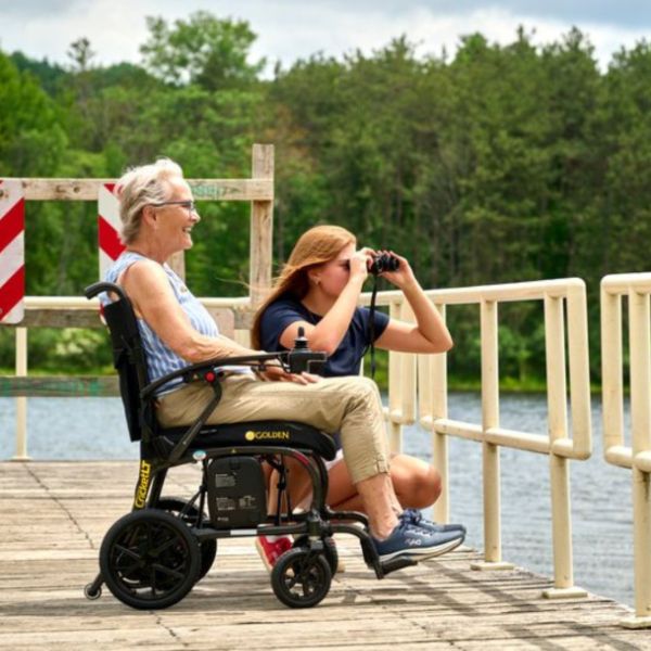 A Woman Sitting on the Golden Cricket LT Carbon Folding Power Wheelchair 