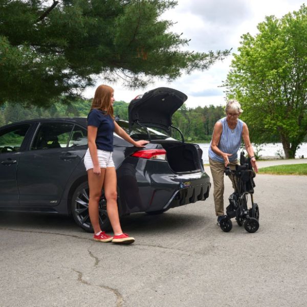A Woman Folding the Golden Cricket LT Carbon Folding Power Wheelchair