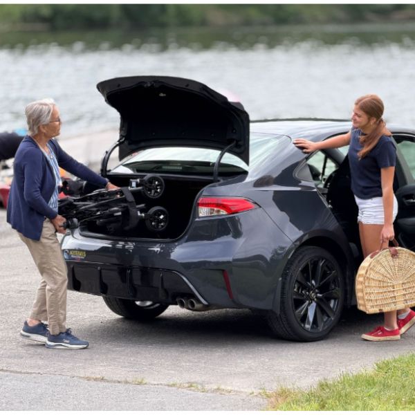 A Woman Putting the Golden Cricket LT Carbon Folding Power Wheelchair Inside the Trunk