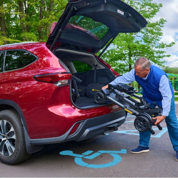 A man placing the Buzzaround CarryOn HD Inside his Car Trunk