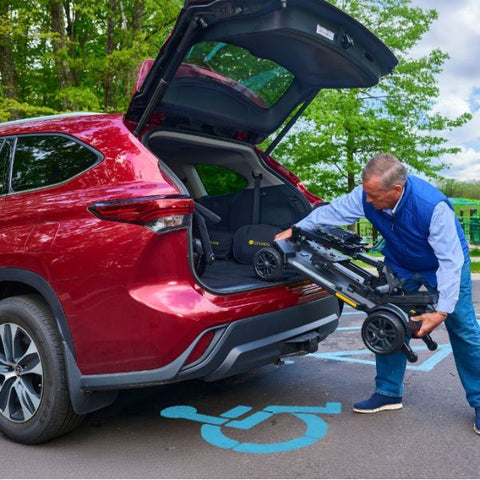 A man placing the Buzzaround CarryOn HD Inside his Car Trunk