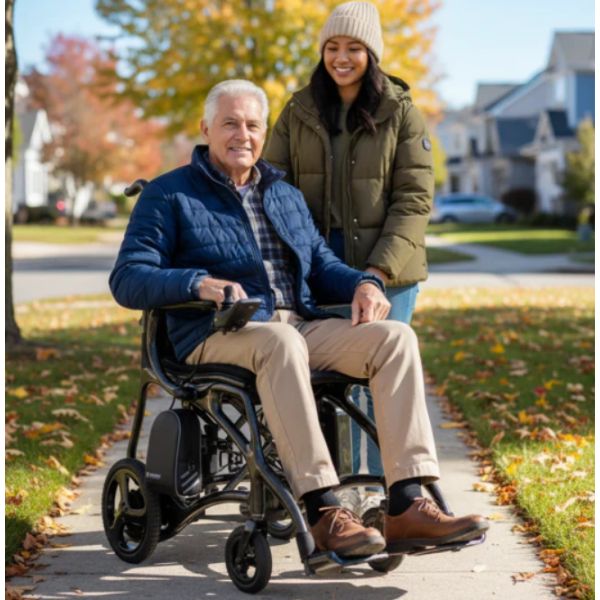 A Man Riding on Journey Air Elite Max Portable Folding Power Wheelchair with a Lady Behind Him