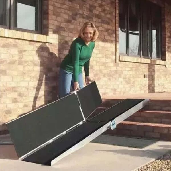 Woman setting up a PVI Multi-fold Bariatric Ramp outside a building.