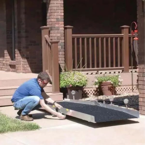 Person installing the PVI Wheel-A-Bout Portable Wheelchair Ramp on a home entrance.