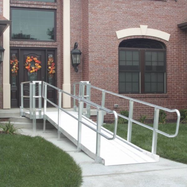 PVI XP Modular Wheelchair Ramp with Handrails leading to a brick building with a door and flowers.