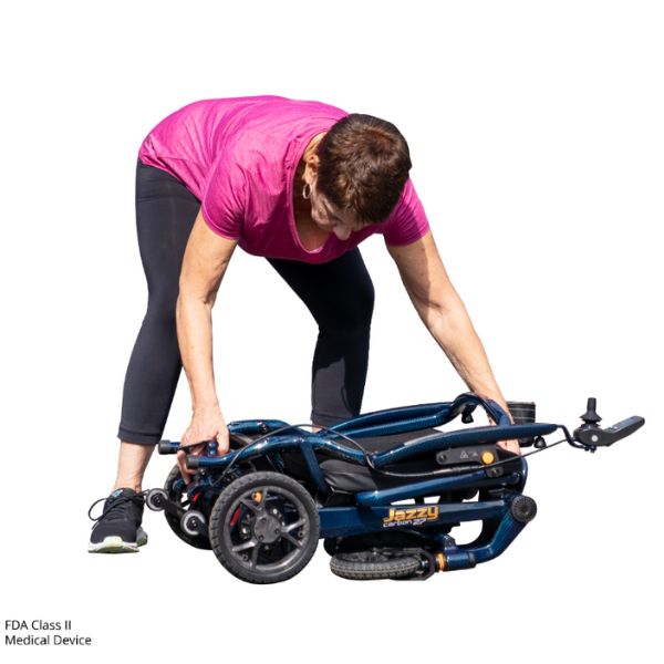 A woman folding the Pride Jazzy Carbon 27 Folding Power Wheelchair in Blue