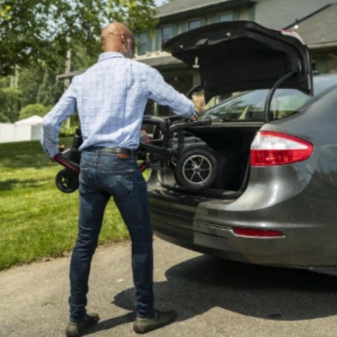 Man putting the folded up Feather Lightweight Electric Scooter  in the back of a car's trunk